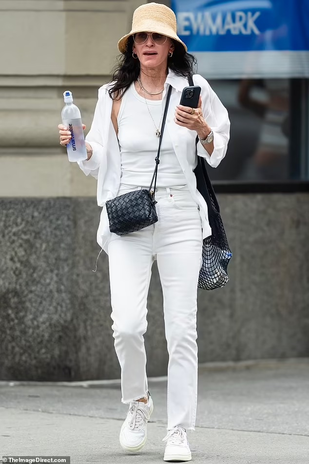 Summer Elegance: Courteney Cox’s Effortless White Outfit and Straw Hat in NYC on July 27, 2023